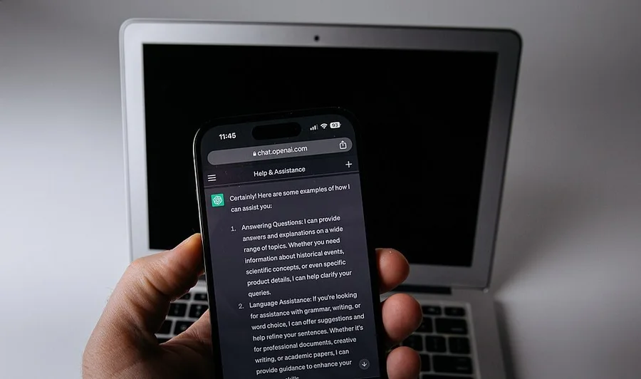 Смартфон с чат-ботом на фоне ноутбука