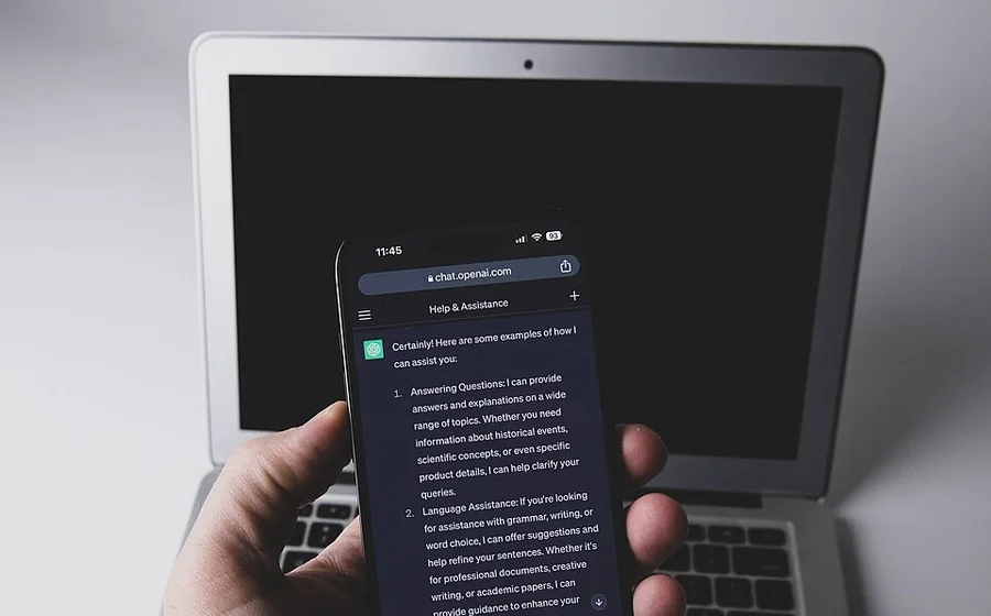 Смартфон с открытым ChatGPT на фоне ноутбука