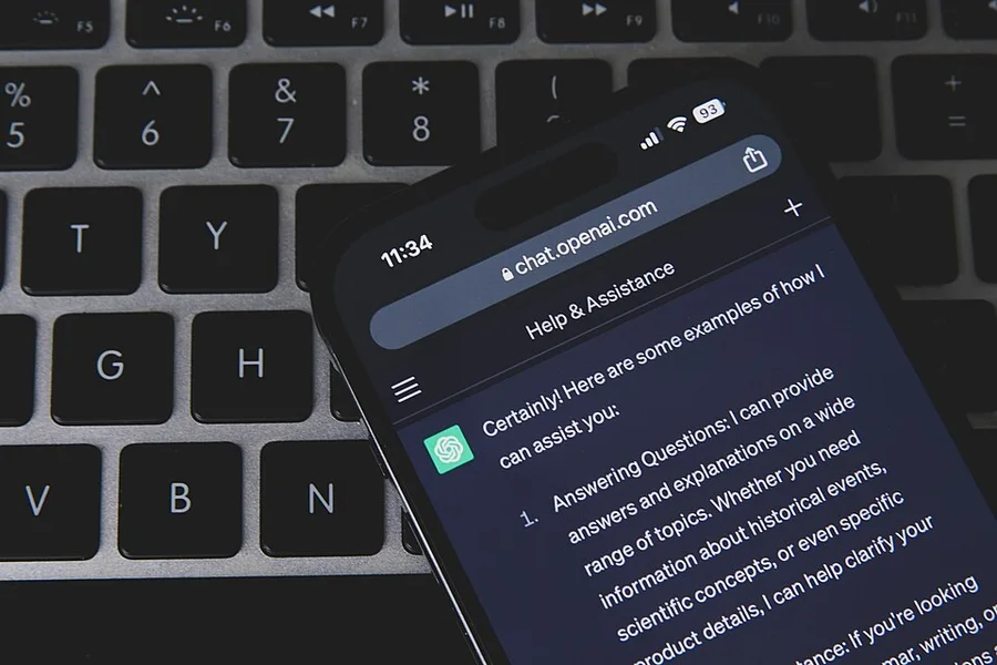 Смартфон с чат-ботом на клавиатуре ноутбука